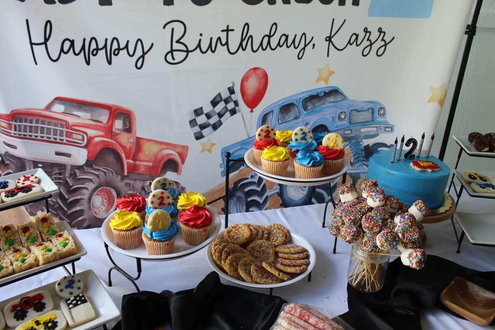 A birthday dessert table with cupcakes, cookies and a themed backdrop