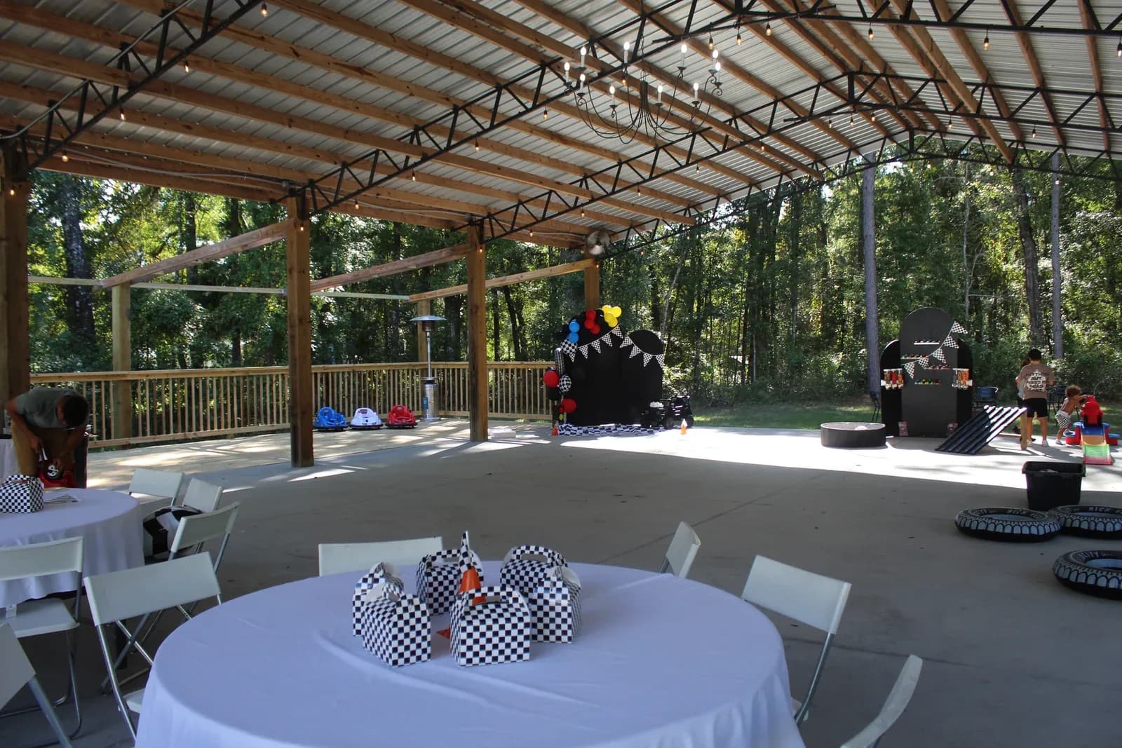A children's birthday party set up under the pavilion, tables in checkered cloths with balloons