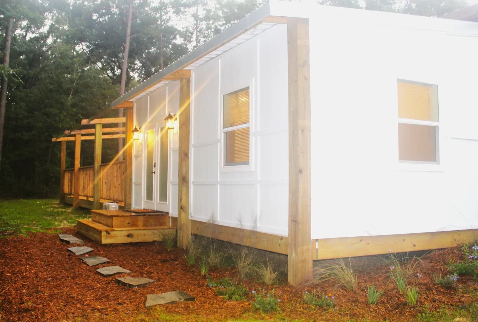 The bridal suite from outside at dusk, a white cabin with a cedar walkway and lit lanterns beside the door