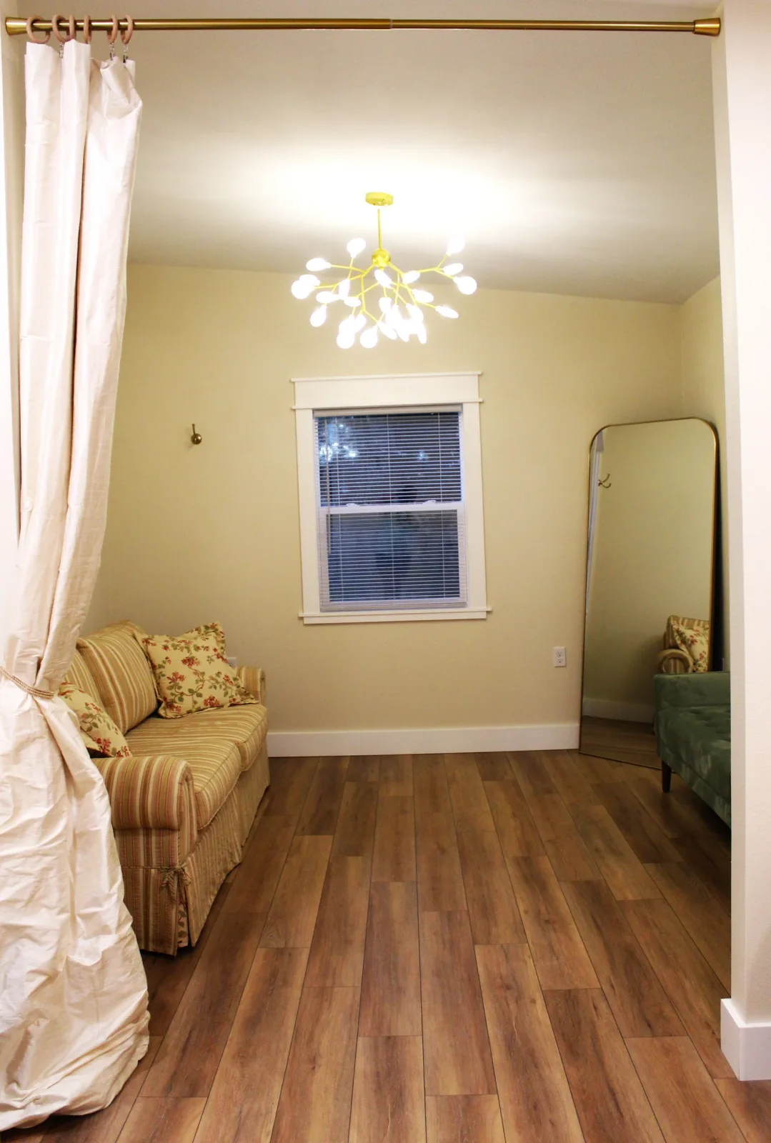 The bridal suite lounge, with a brass chandelier, a full-length mirror and a sofa on wood floors