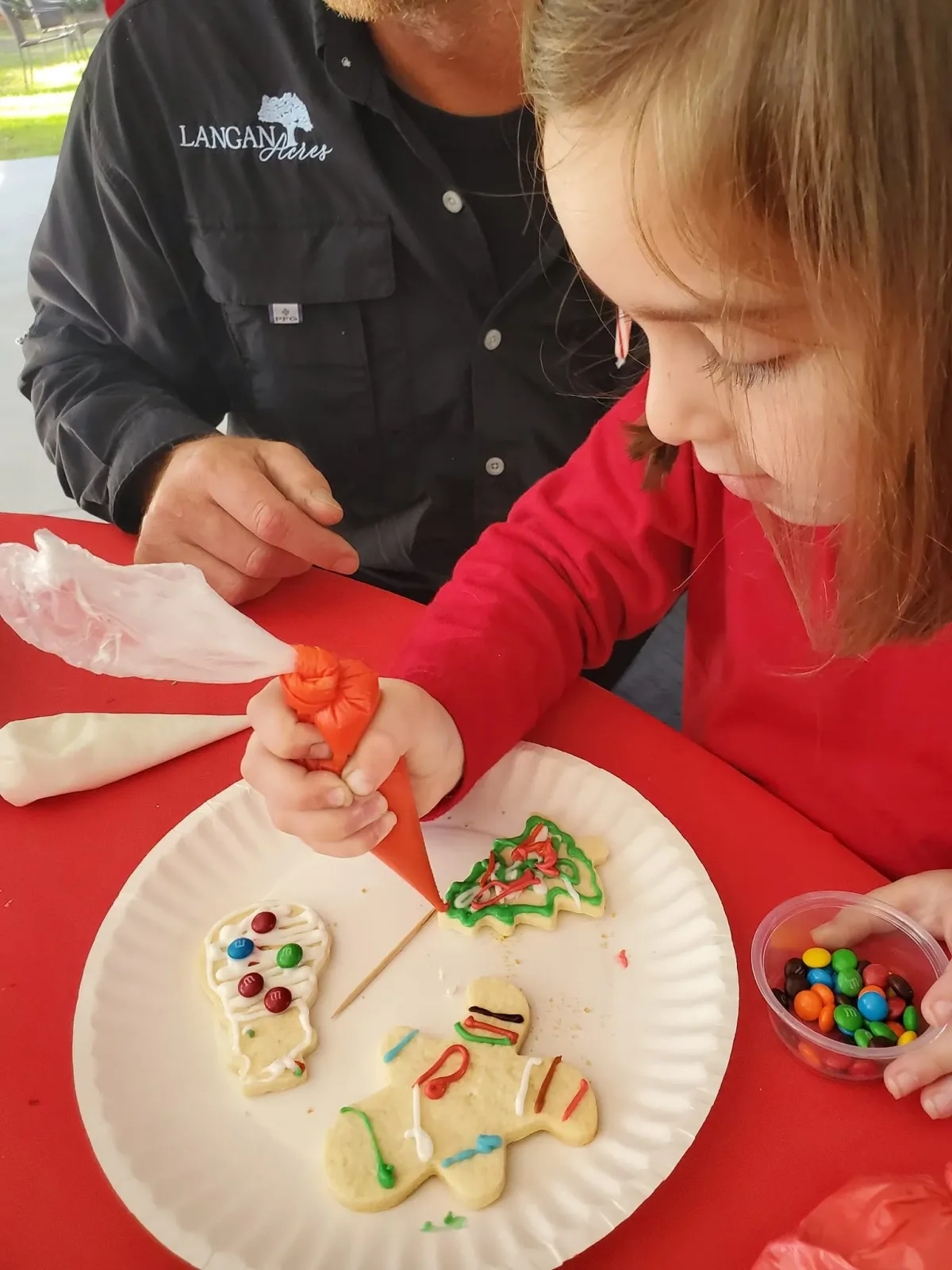A child piping icing onto a gingerbread cookie at a decorating class