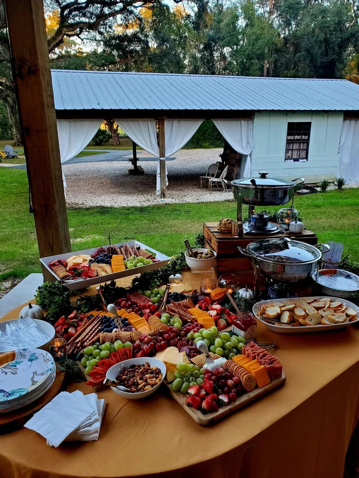 A long grazing table of cheeses, fruit and cured meats laid out on a wooden board