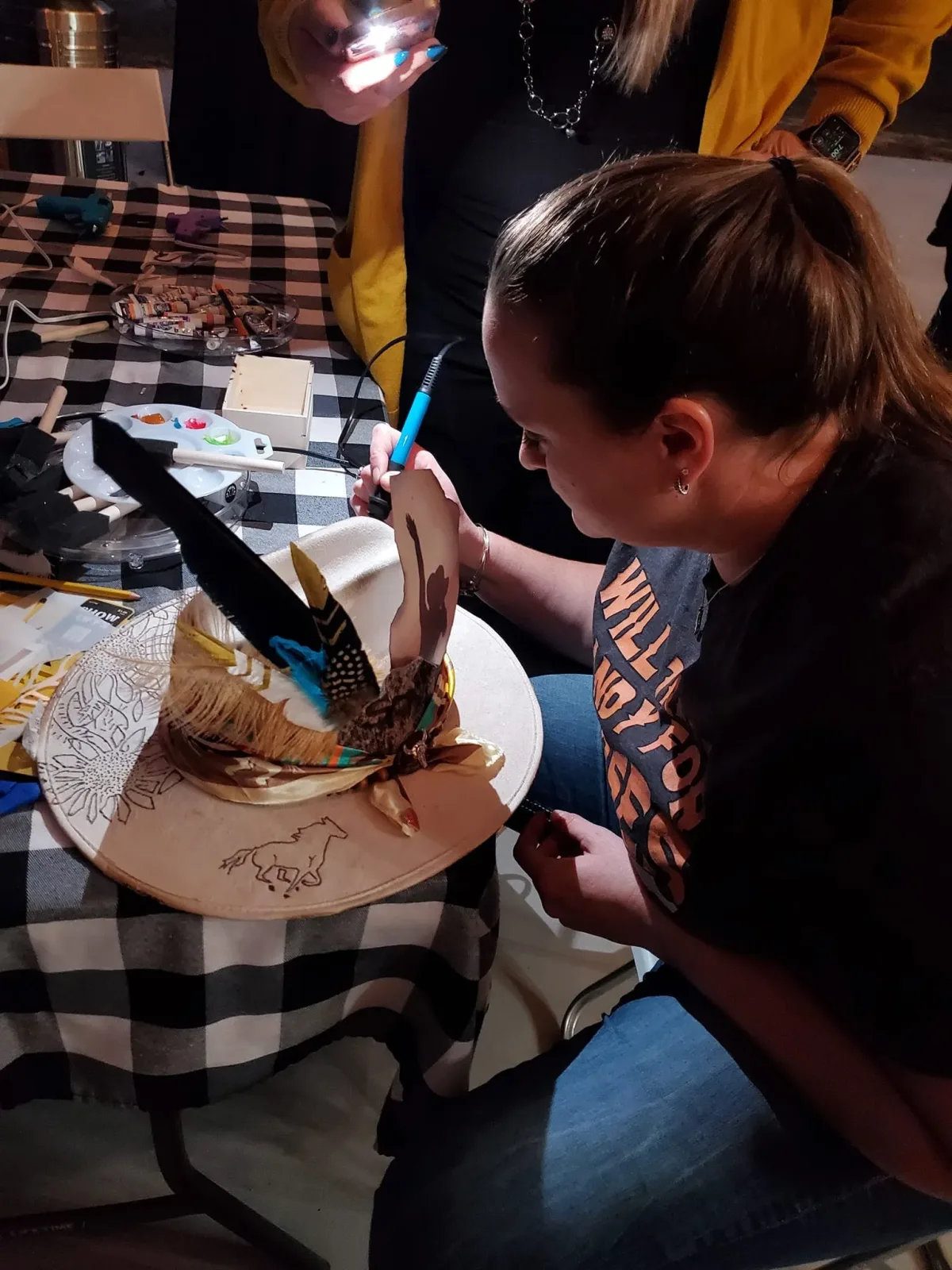 A woman burning a design into the brim of a felt hat during a hat-making class
