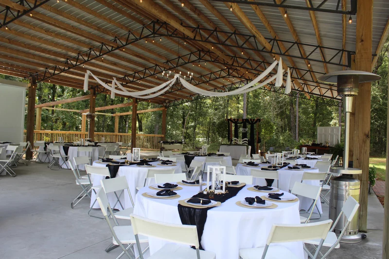 Round tables in white linen with black napkins, laid out under the pavilion
