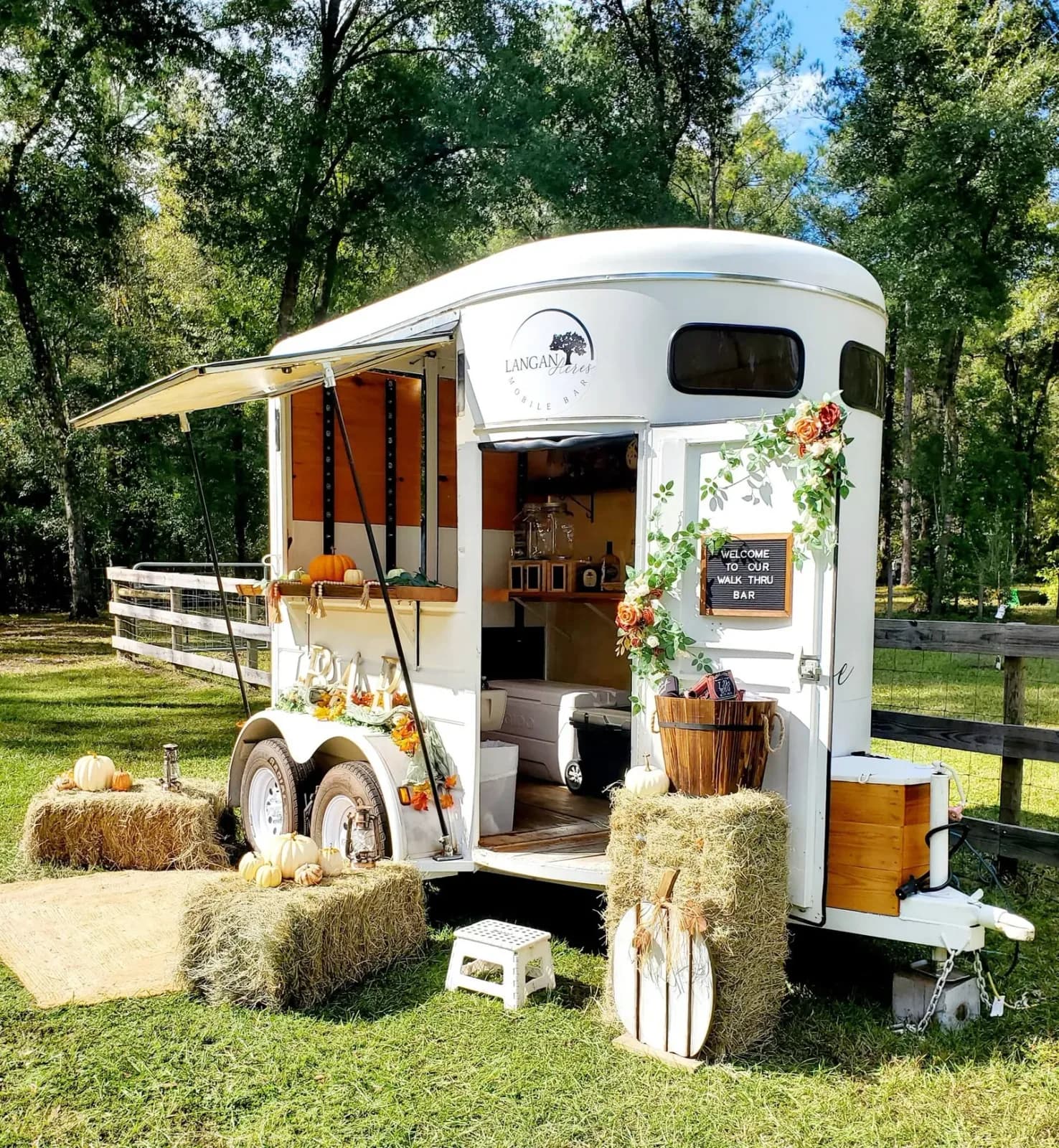 Reese the mobile bar parked on the grass in autumn, hay bales and pots of mums arranged at the serving window