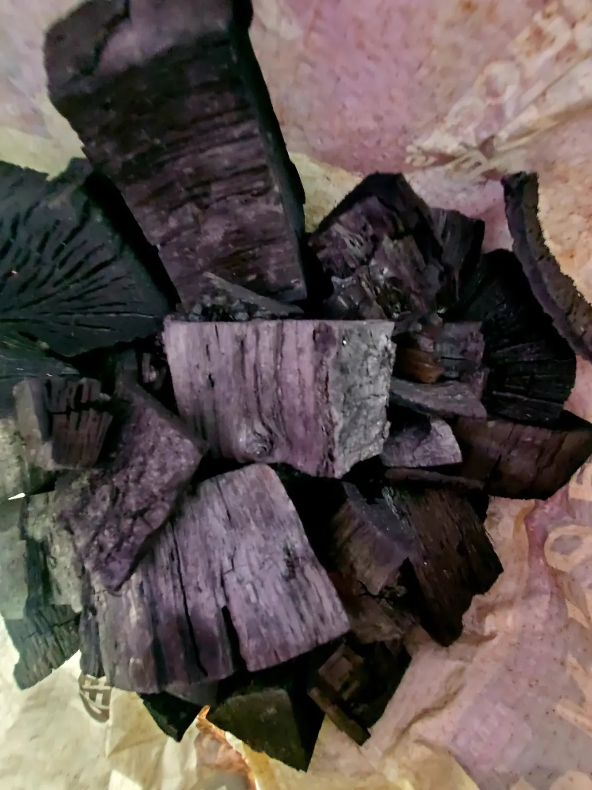 Homemade lump charcoal made on the farm, irregular blackened pieces still holding the grain of the wood they came from.